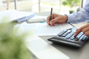 Man seated at a desk with a business calculator, preparing taxes.