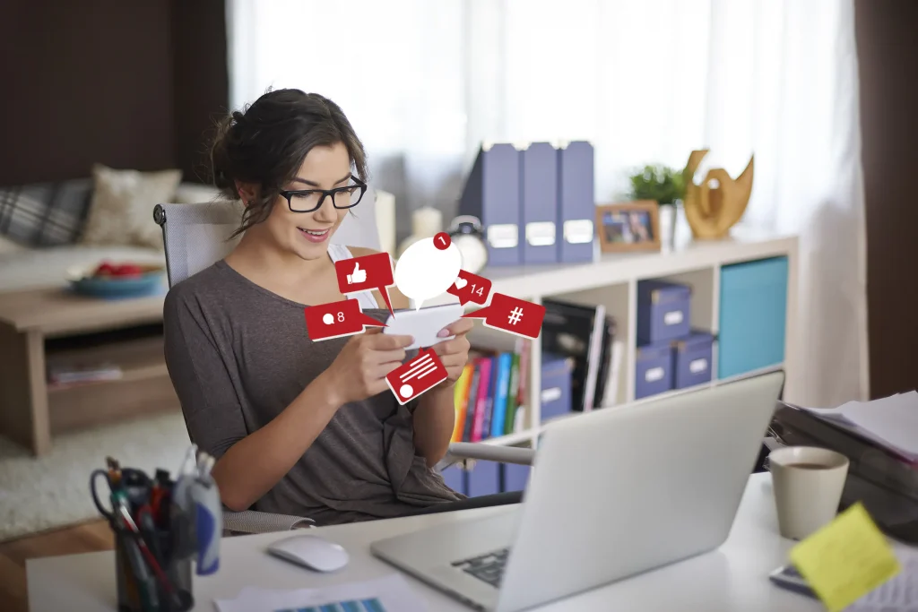 A young woman in an office setting using social media on her cell phone.