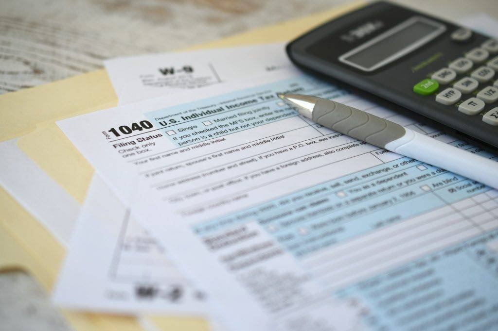 IRS 1040 Tax return form with ink pen and calculator. Filing income taxes before the deadline.